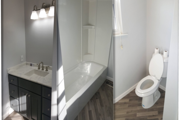 A custom remodeled bathroom with a new bathroom vanity with a marble vanity top, a new bathtub and shower combination, a new toilet, and new flooring and painted gray painted walls. 