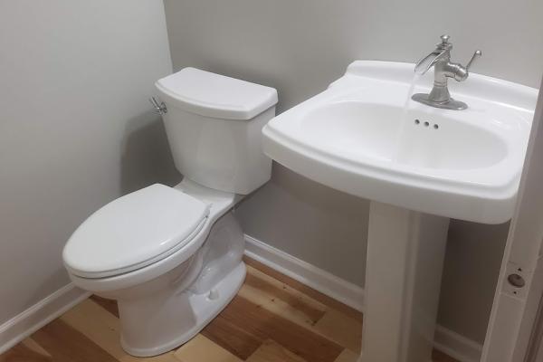 White porcelain pedestal sink with a waterfall faucet and a close coupled toilet. 