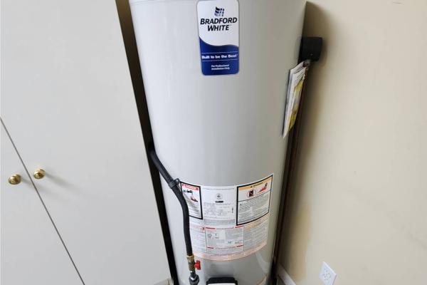 A newly installed 50-gallon Bradford White natural gas water heater, complete with a drain pan for leak protection and a chimney flue for safe venting. Professionally installed by Applause Plumbing and Heating in Stewartsville, NJ, ensuring reliable hot water for the homeowner.